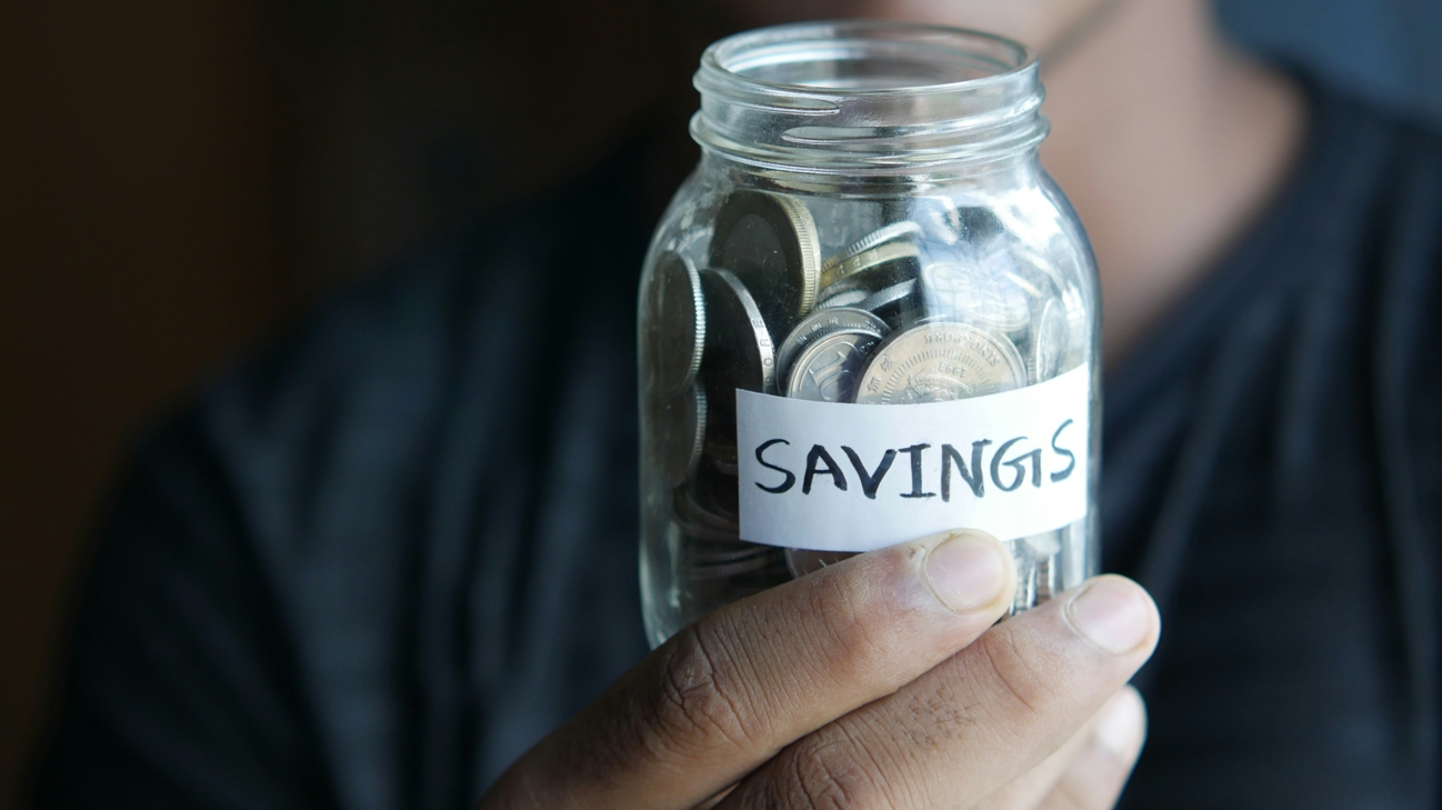 동전이 담긴 병을 손에 들고 저축을 상징하는 이미지